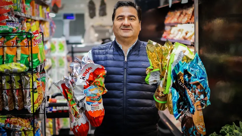 Nuno holding chocolate Easter eggs in colorful wrappers in a Victor’s aisle